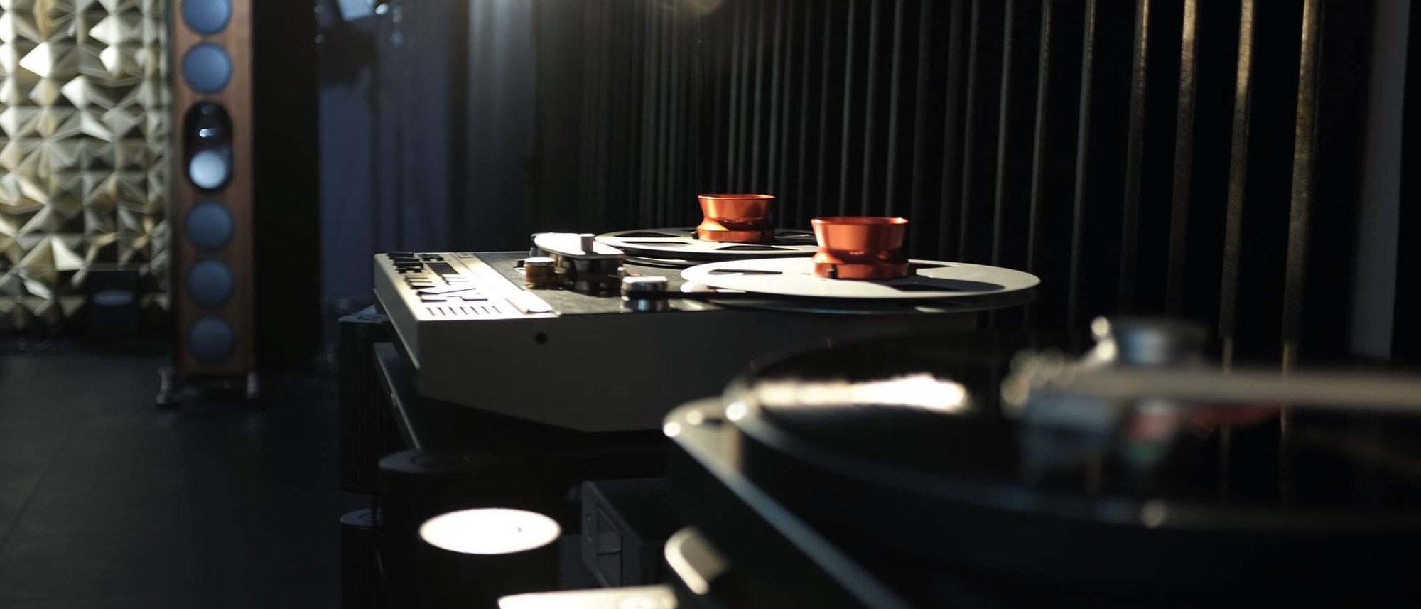 A turntable and electronics on a black table, a loudspeaker behind them