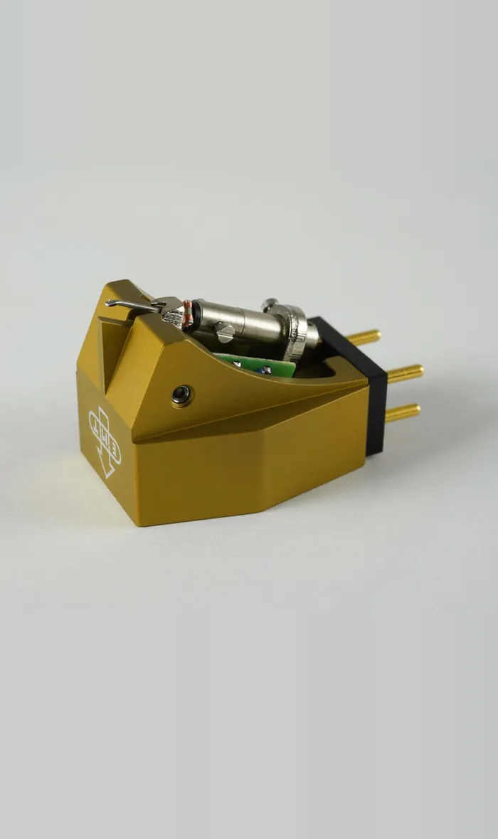 An EMT HSD SC6 cartridge in gold, from the front and to one side, its gold pins at the back, on grey