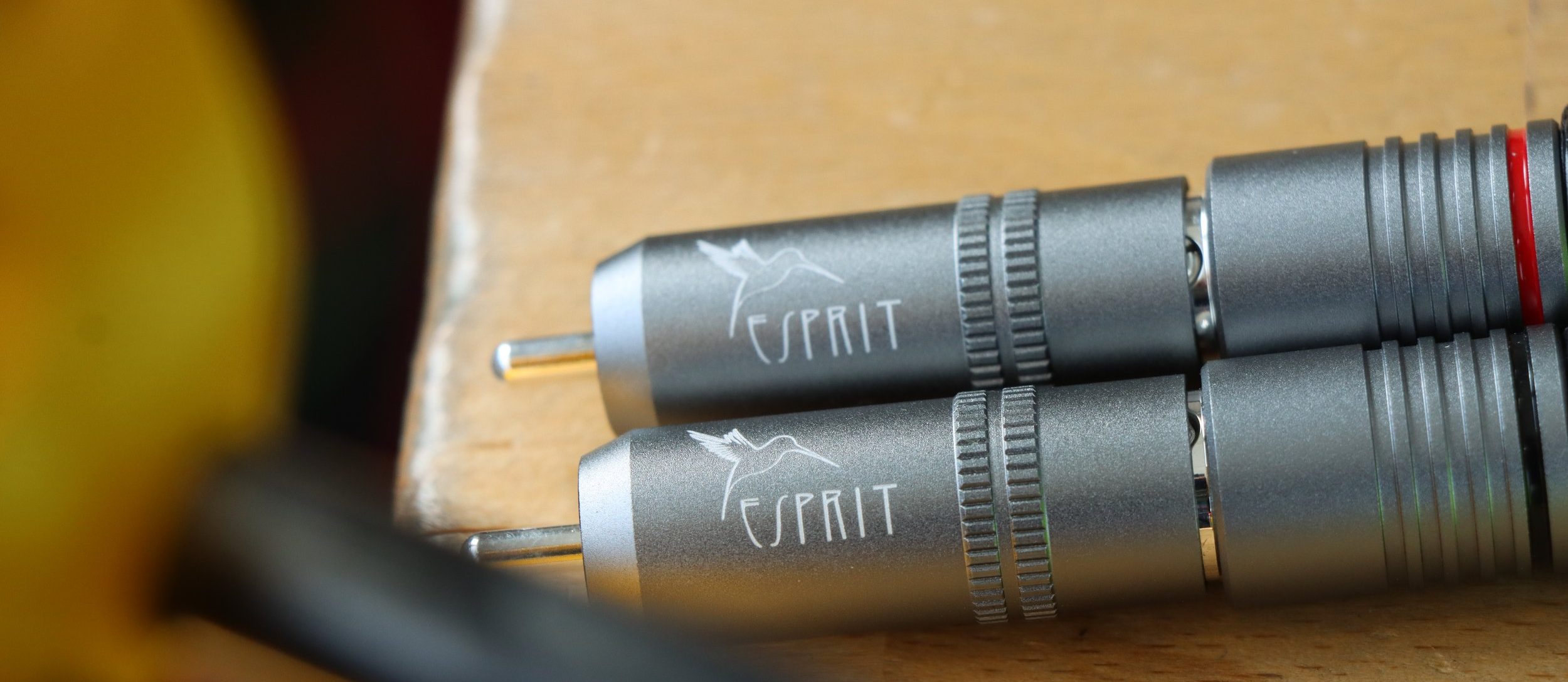 Two Esprit RCA plugs, their barrels engraved with the maker's bird, on a wooden bench