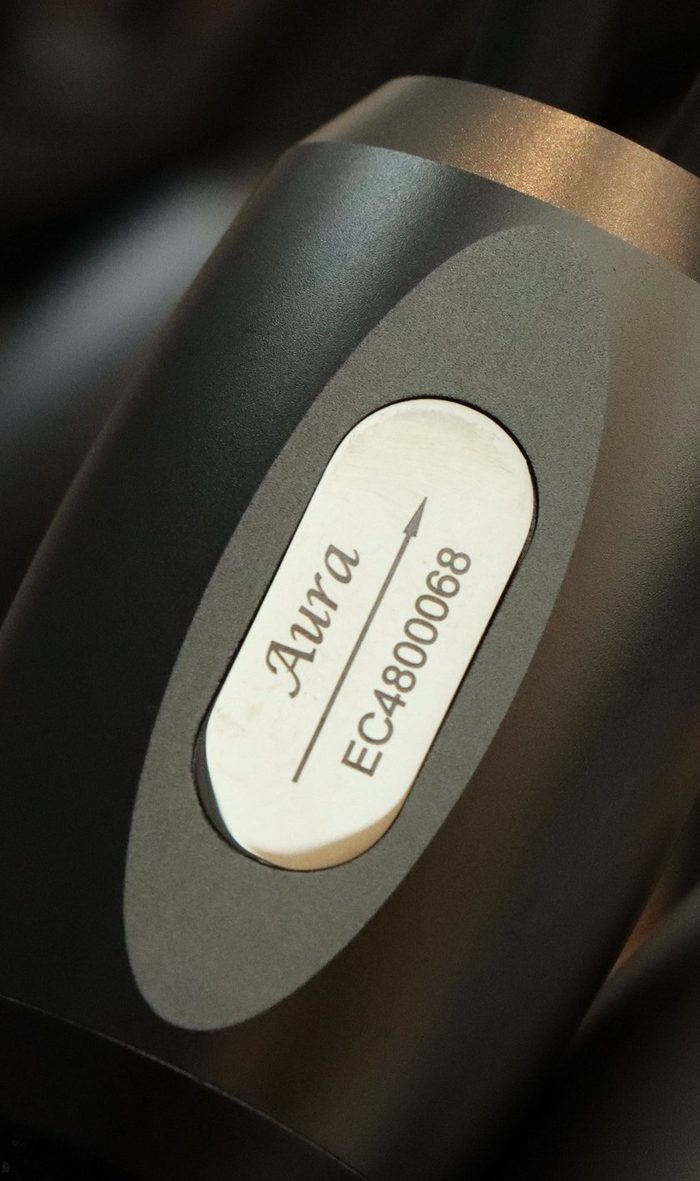 The Aura badge on a black braided cable
