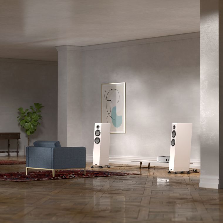 A room with an armchair facing a pair of white loudspeakers