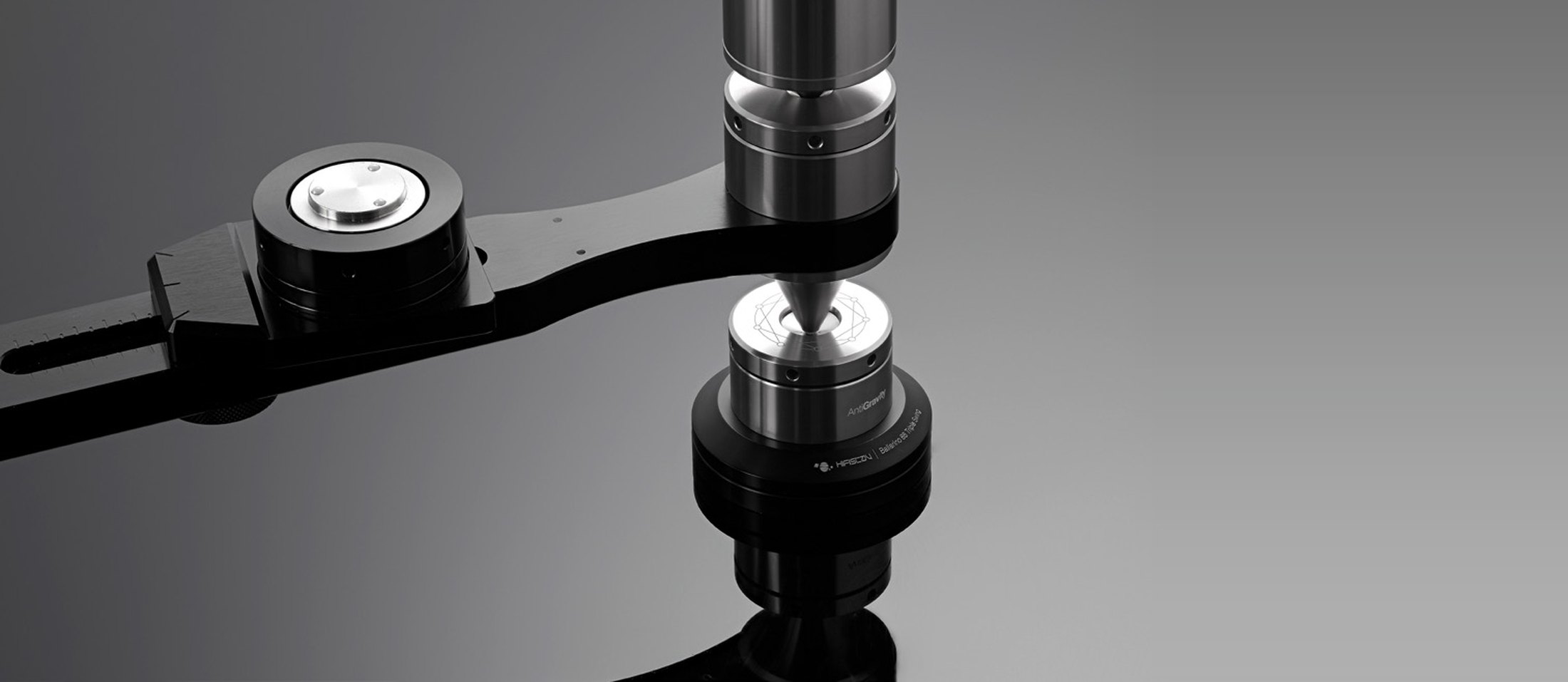 The joint of a HifiStay X-Frame rack, close: a steel column on a spike over a black arm, on a dark ground