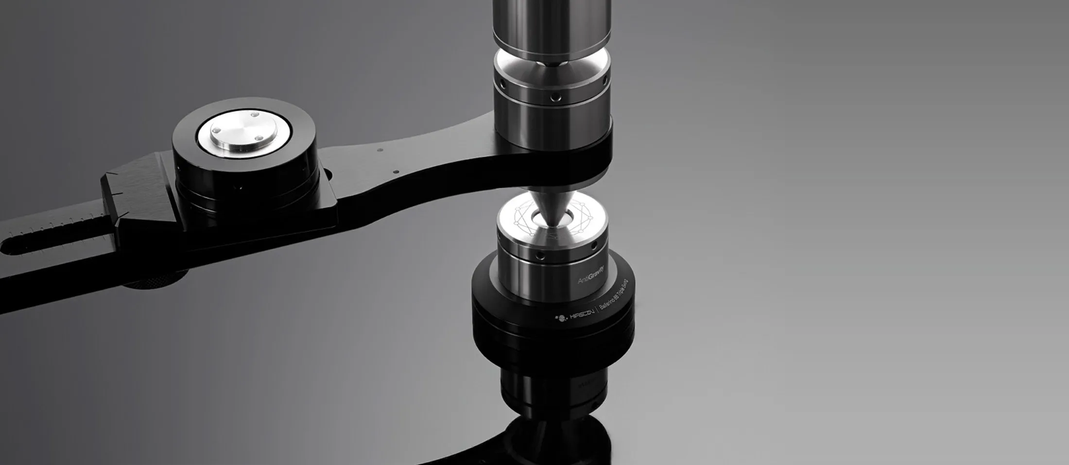 The joint of a HifiStay X-Frame rack, close: a steel column on a spike over a black arm, on a dark ground