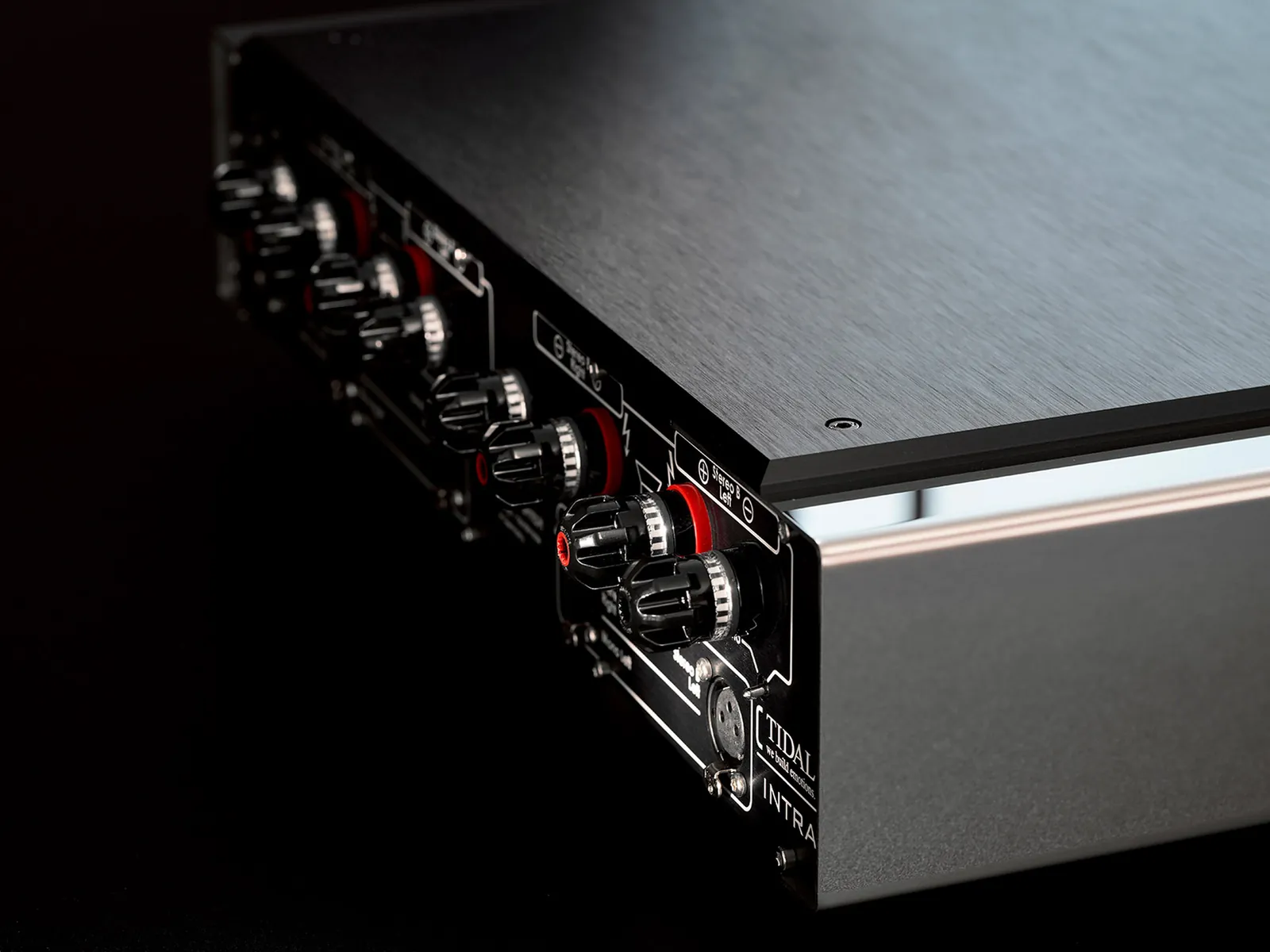 The back of a TIDAL Intra amplifier, its loudspeaker terminals in red and silver, on black