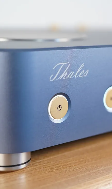 The front corner of a Thales Magnifier in blue, its Thales script and power button, on a wooden shelf