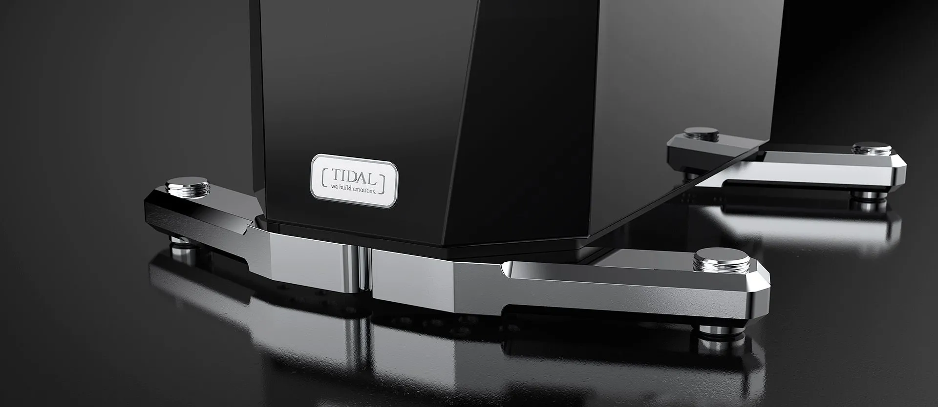 The polished aluminium foot of a TIDAL loudspeaker in black lacquer, its nameplate above, on a black floor
