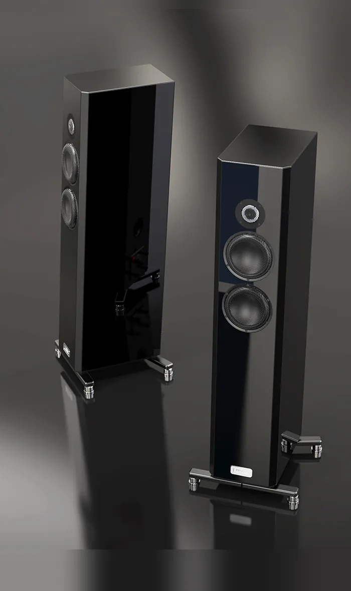 A pair of TIDAL Piano Classic loudspeakers in black lacquer, one behind the other, on a dark reflective floor