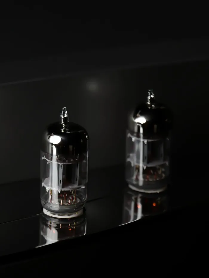 Two valves lit on the black mirrored top of a phono stage