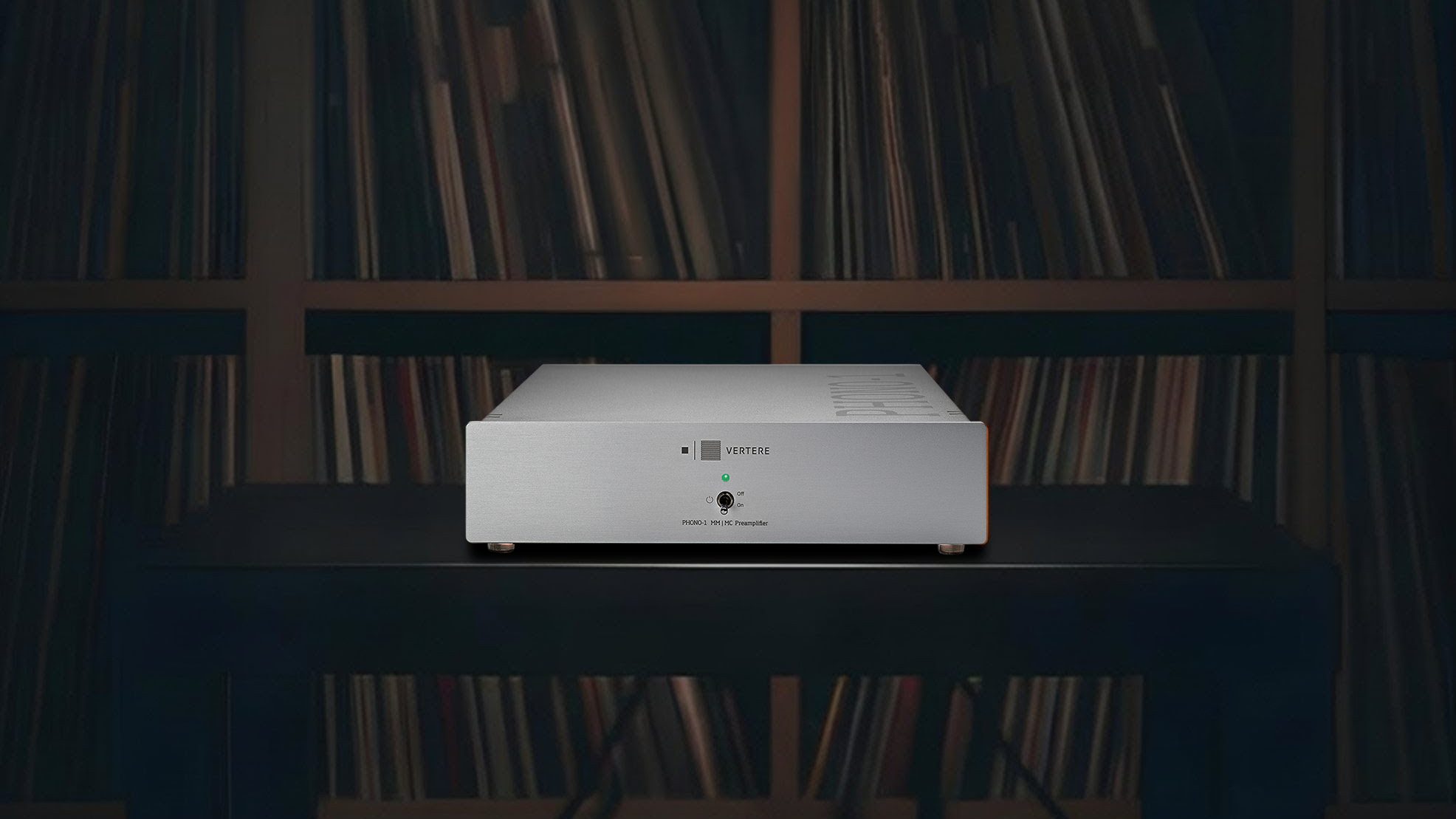 A Phono-1 LX phono stage in silver on a dark rack, shelves of records behind it