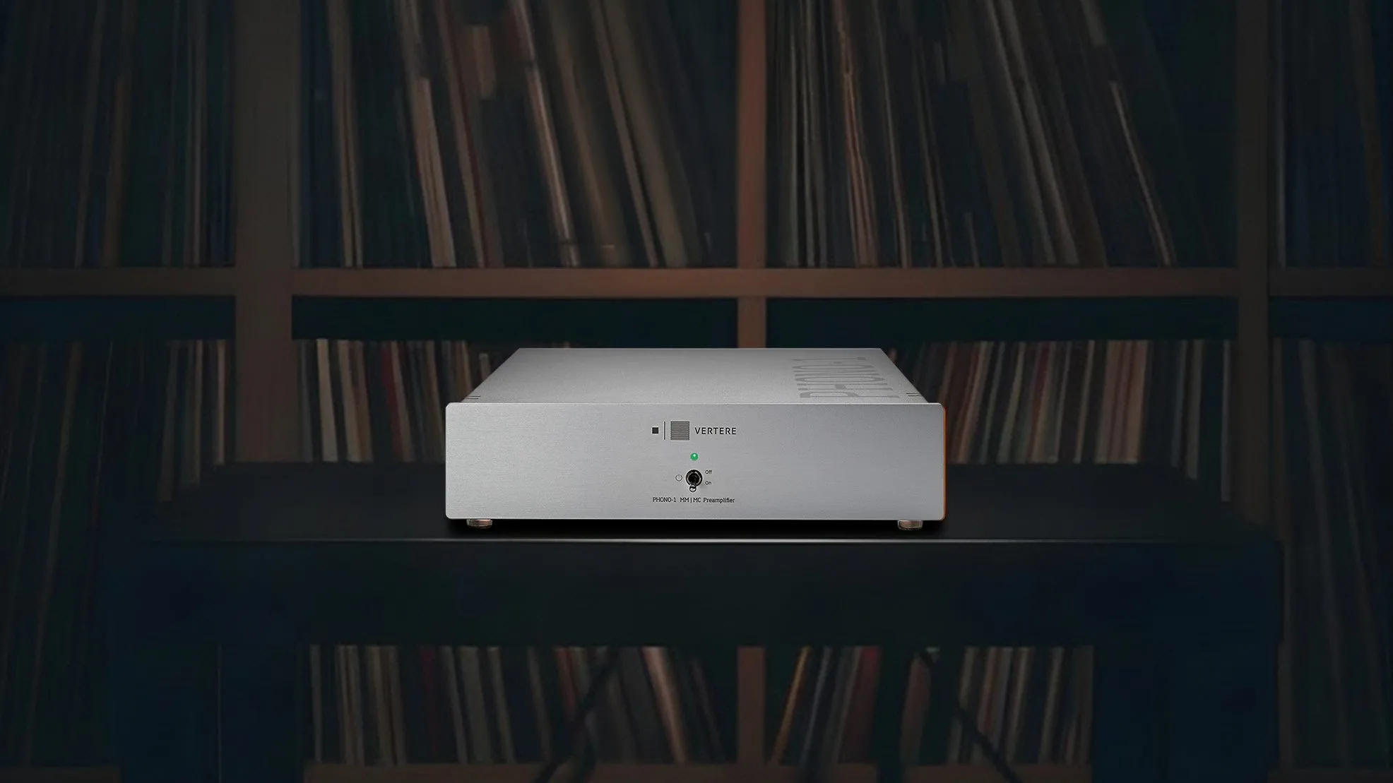 A Phono-1 LX phono stage in silver on a dark rack, shelves of records behind it