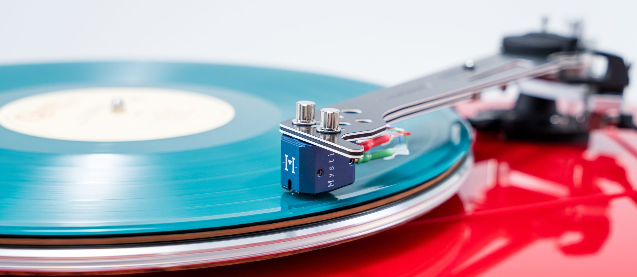 A blue Mystic cartridge on a turquoise record, on a red Vertere turntable